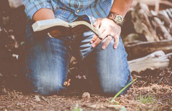 person reading book while kneeling