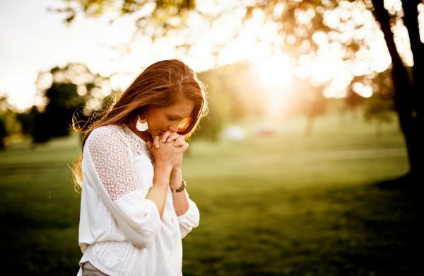 woman praying beside tree